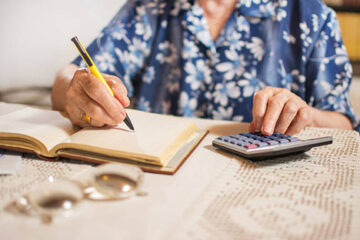 Close-up of unrecognizable senior woman doing finances at home.